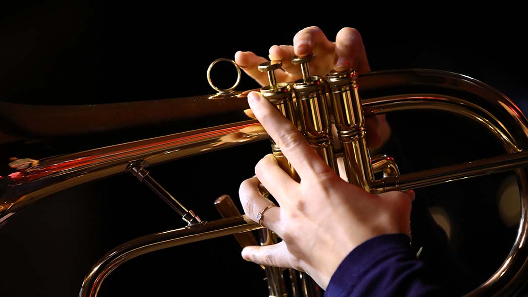 A close up of a white person playing a trumpet
