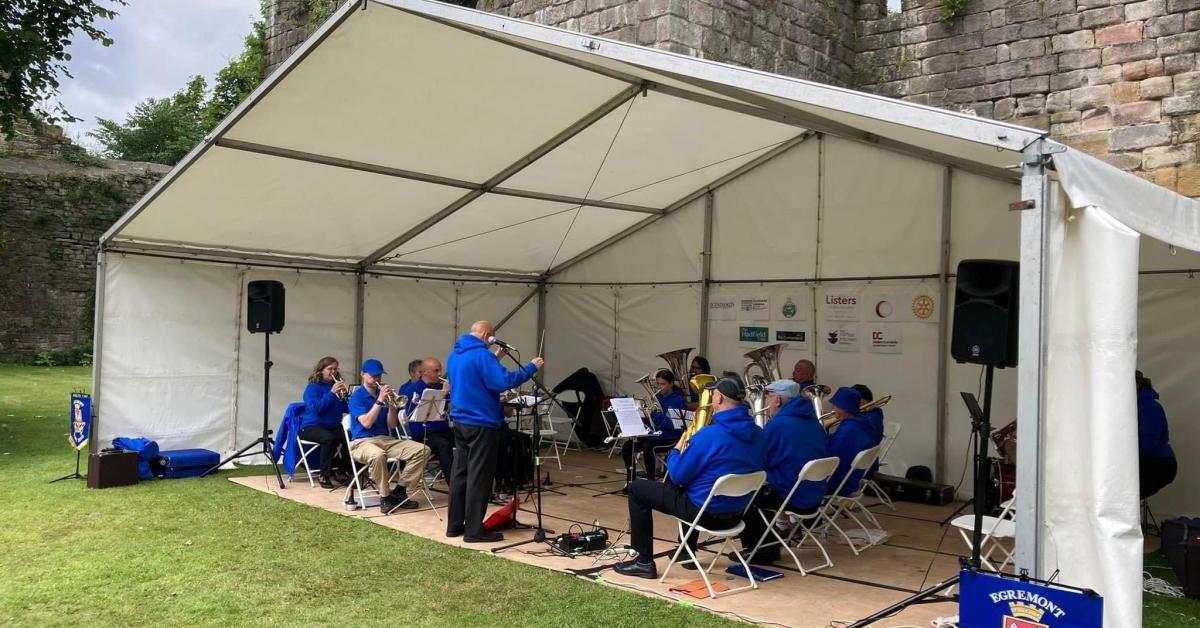 A brass band performing in a large tent outside.