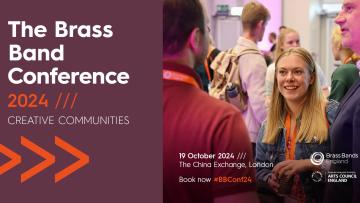 Woman with long blond hair is talking to a man and smiling, she is wearing an orange lanyard